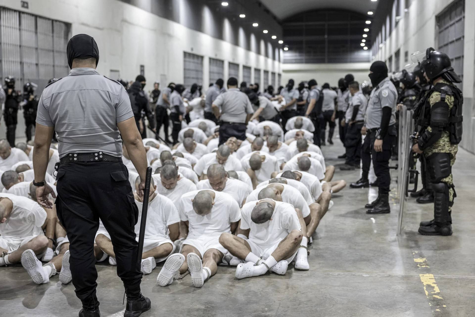 In this photo provided by the president of El Salvador's press office, a prison guard transfers deportees from the U.S. alleged to be from Venezuelan gangs, to the Terrorism Confinement Center in Tecoluca, El Salvador, on March 16, 2025. (Credit: AP.)
