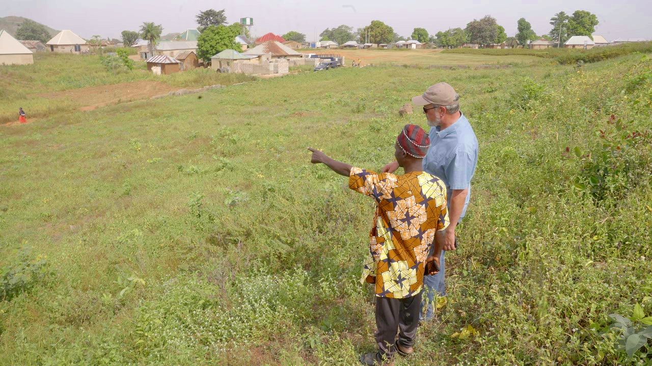 Mike Arnold speaks with Yohanna A Ngbako, the chief in the area of the Wasa IDP camp outside Abuja, marking off ground that Africa Arise has acquired for building a school. (Credit: Given by Mike Arnold.)