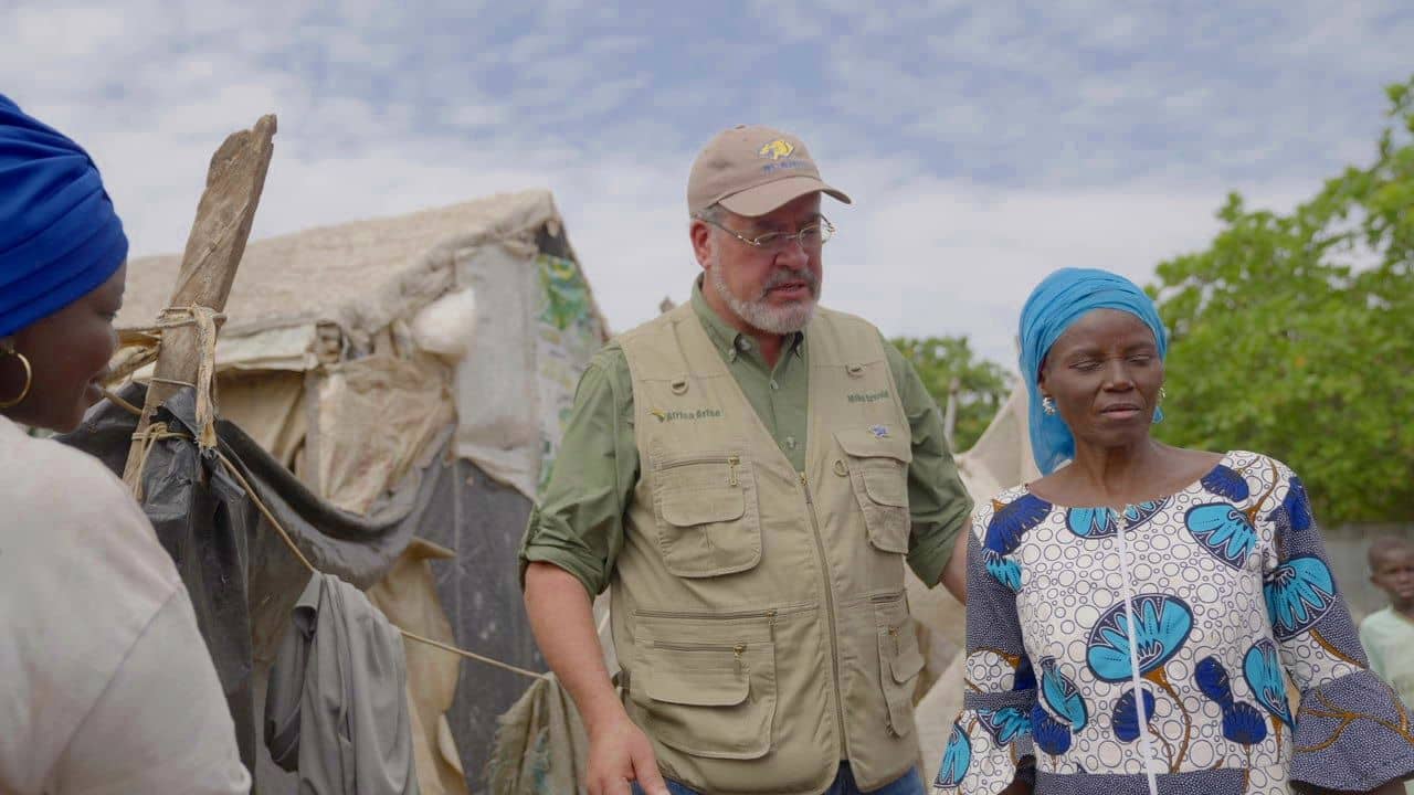 Mike Arnold – the mayor of Blanco, Texas - and IDP Ms. Hanatu Ango speak in the New Kuchingoro camp in Abuja. Ango is the head teacher of the school sponsored by the Africa Arise charity. She and two other IDPs were teaching some 250 children in camp without support for several years before she met Arnold. (Credit: Given by Mike Arnold.)